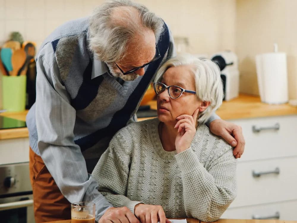 An older couple reviewing important paperwork together at their kitchen table