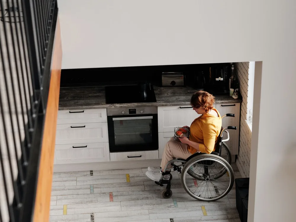 A wheelchair user preparing food in a bright, open kitchen